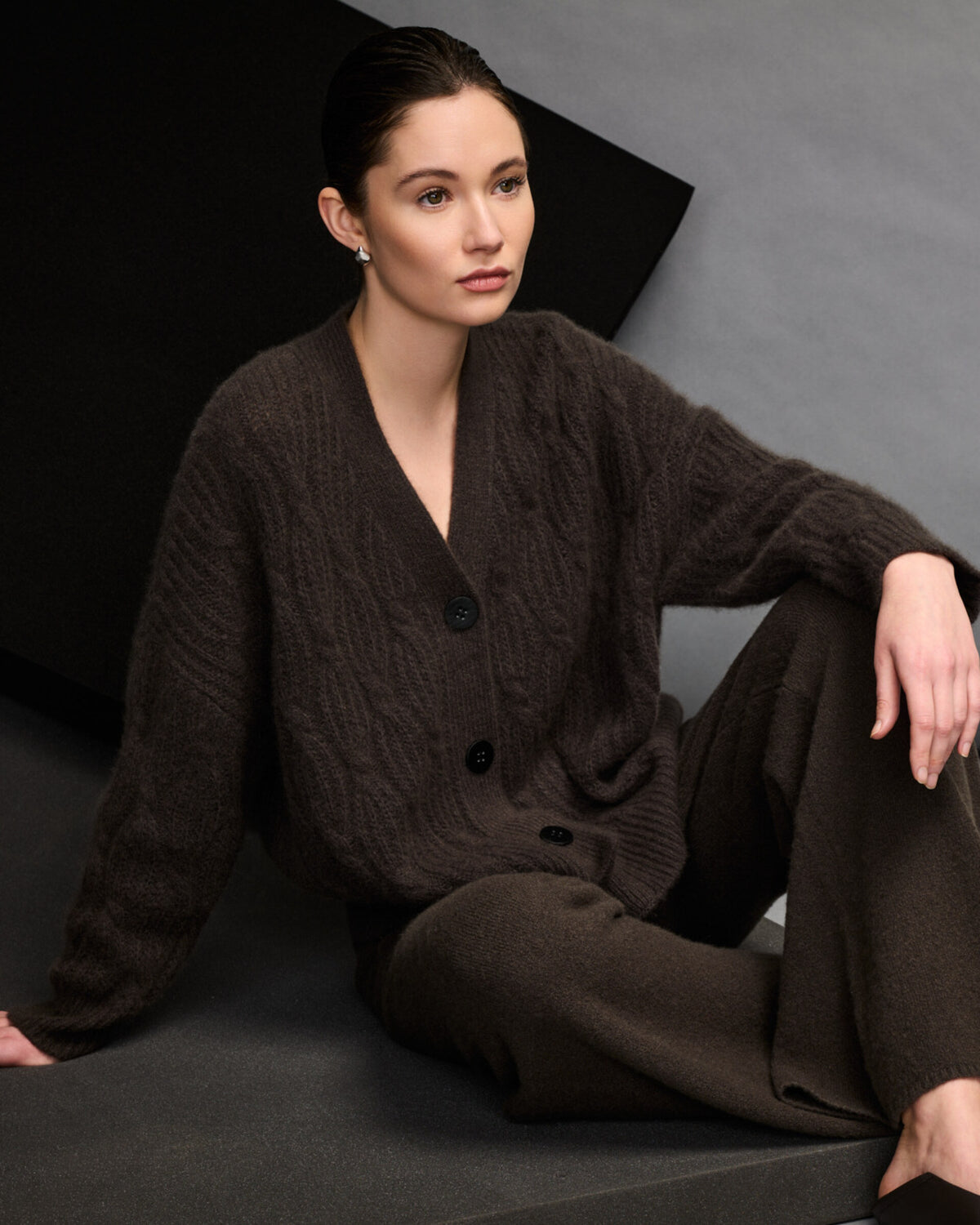 Damen Cardigan aus 75 % Kaschmir und 25 % Seide in Black Forest – Cardigan mit Zopfstrickmuster in mittelschwerer Qualität und oversized Passform mit langer, weiter Silhouette. Das Modell verfügt über eine Knopfleiste mit Knöpfen aus waschbarem Leder, eine überschnittene Schulter sowie lange, relaxte Ärmel. Ärmelbündchen und Saum sind in Rippstruktur gearbeitet und verleihen dem Design einen markanten, zeitlosen Look.