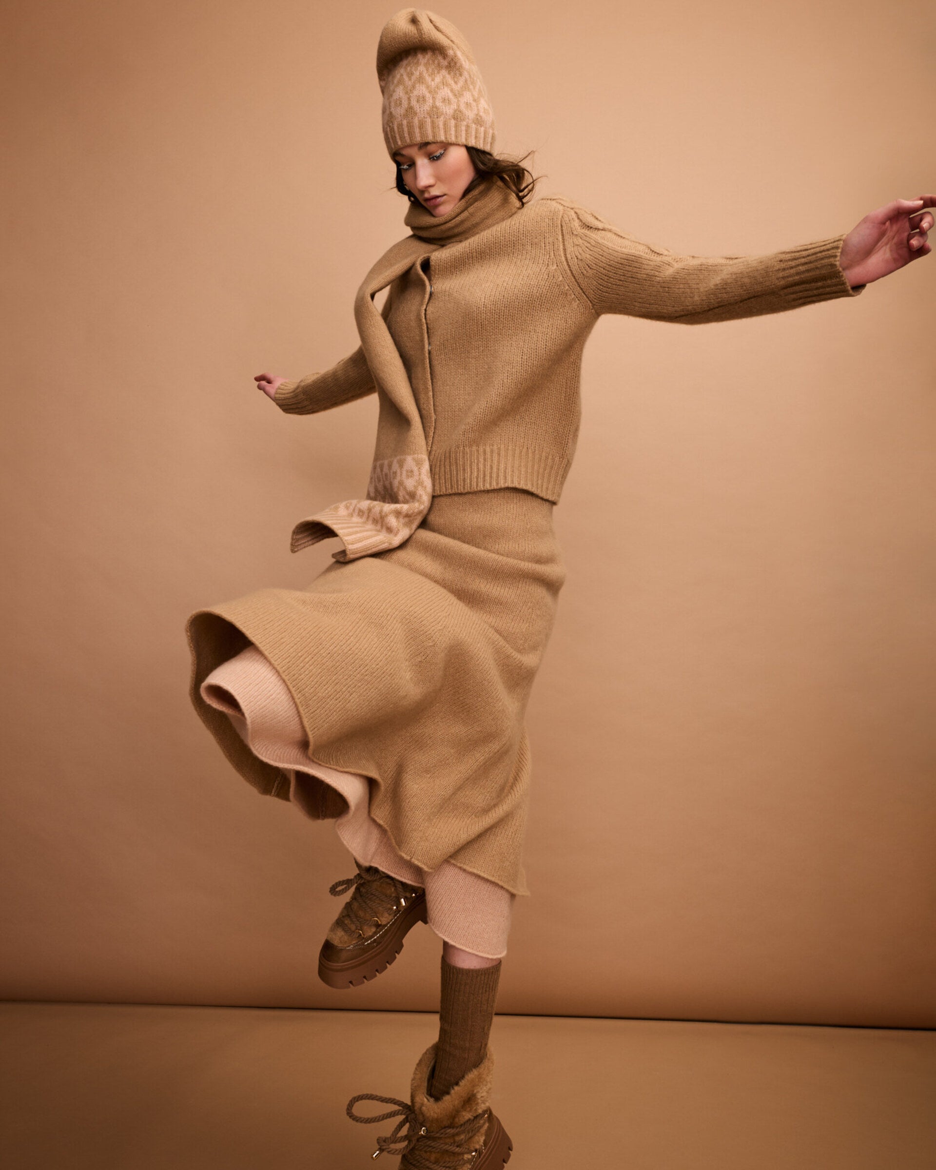 Damen Strickrock aus 75 % Kaschmir und 25 % Seide in Warm Sand – glatt gestrickter Rock in grober Strickqualität mit figurbetonter A-Linie und Midi-Länge. Das Modell verfügt über einen Taillenbund mit Gummizug und verbindet eine feminine Silhouette mit hohem Tragekomfort.
