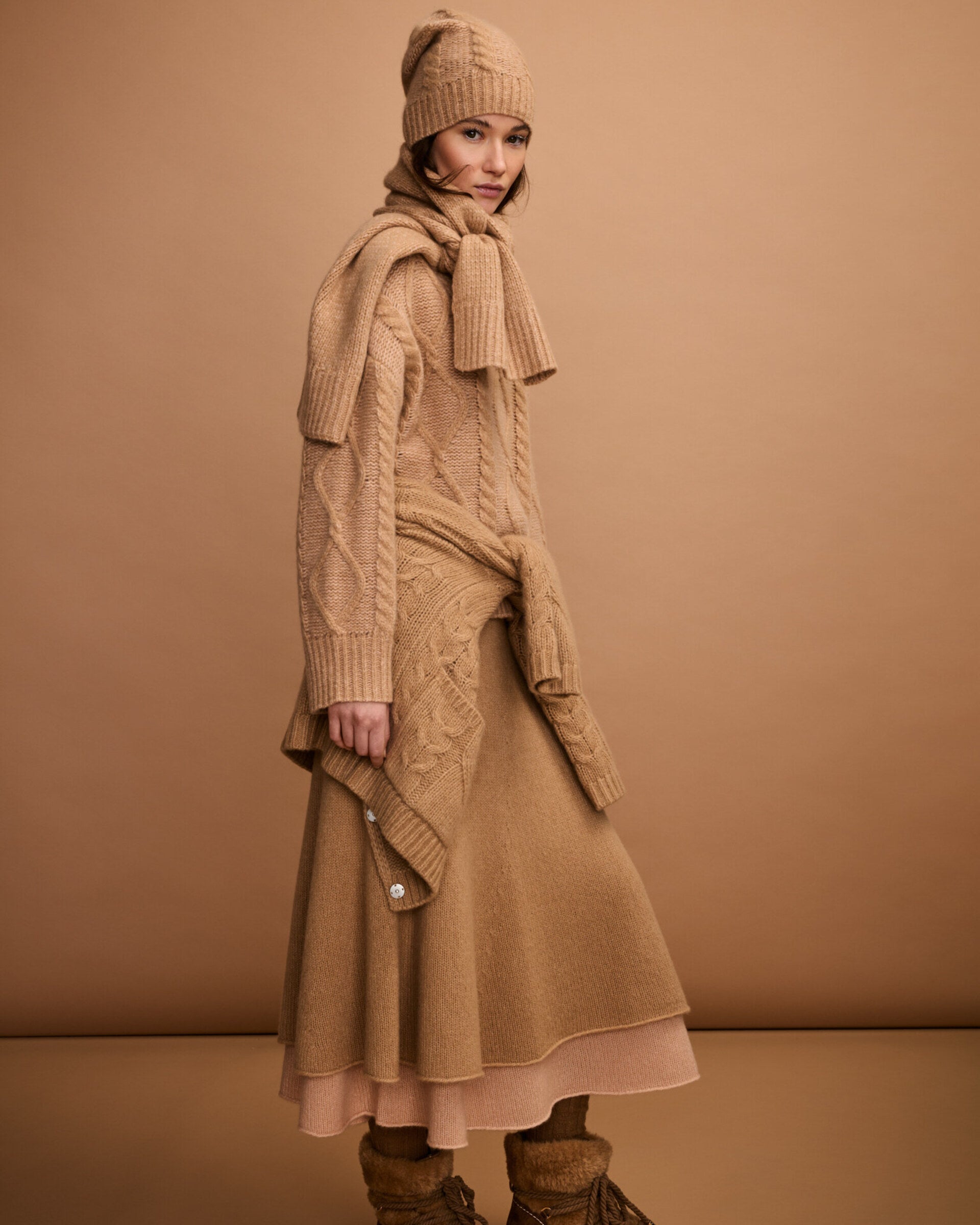 Damen Strickrock aus 75 % Kaschmir und 25 % Seide in Warm Sand – glatt gestrickter Rock in grober Strickqualität mit figurbetonter A-Linie und Midi-Länge. Das Modell verfügt über einen Taillenbund mit Gummizug und verbindet eine feminine Silhouette mit hohem Tragekomfort.
