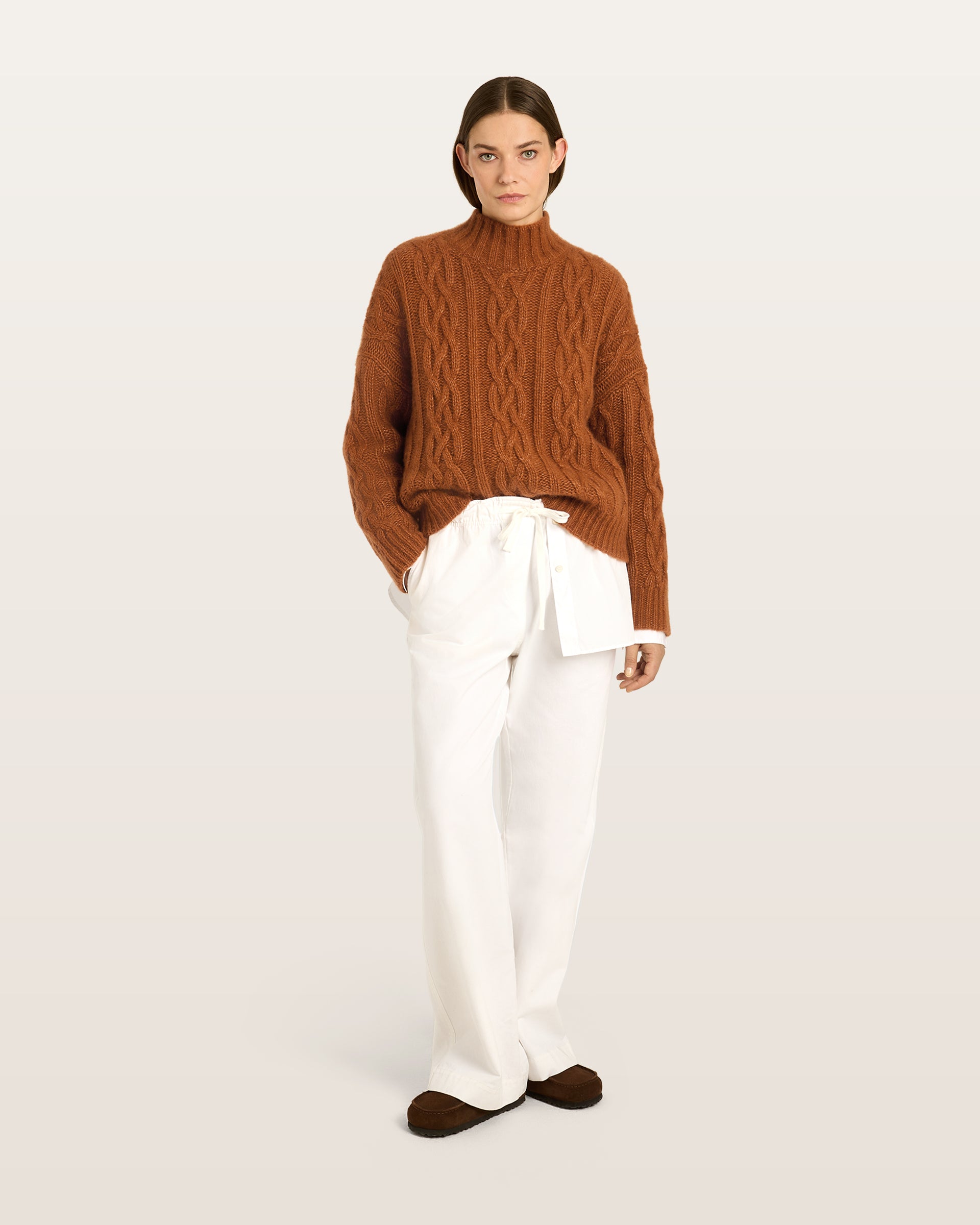 Damen Pullover aus 75 % Kaschmir und 25 % Seide in Bronze – Pullover mit Zopfmuster in grober Strickqualität und oversized Passform, Stehkragen in Rippstruktur, überschnittener Schulter sowie langen, relaxten Ärmeln. Ärmelbündchen und Saum sind in Rippstruktur gearbeitet und verleihen dem Modell einen markanten, zeitlosen Look.
