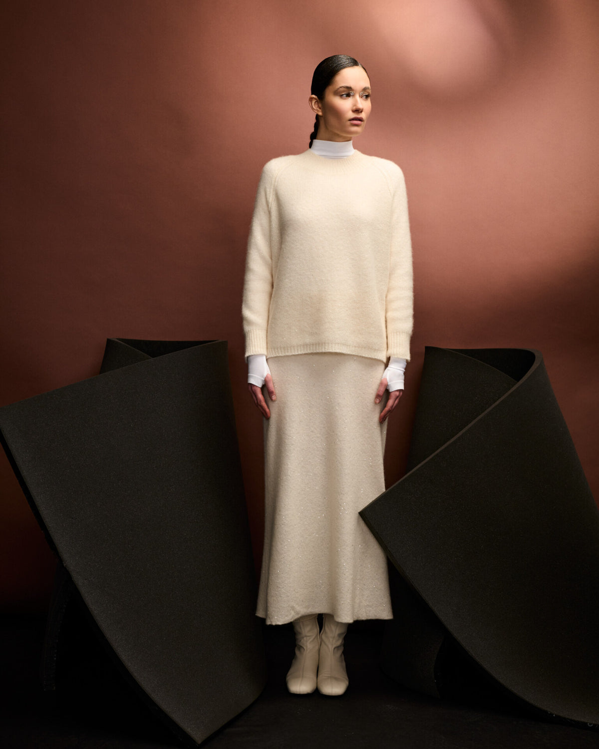 Damen Pullover aus 60 % Kaschmir, 39 % Seide und 1 % Pailletten in Ivory – links gestrickter Pullover in mittelschwerer Qualität mit lockerer Passform und geradem Schnitt. Das lange Modell verfügt über einen Rundhalsausschnitt mit hohem Kragen in Rippstruktur, Raglanärmel sowie lange, relaxte Ärmel. Ärmelbündchen und Saum sind in Rippstruktur gearbeitet. Schlitze an den Seitennähten und dezent eingearbeitete Pailletten verleihen dem Pullover eine moderne, elegante Ausstrahlung.
