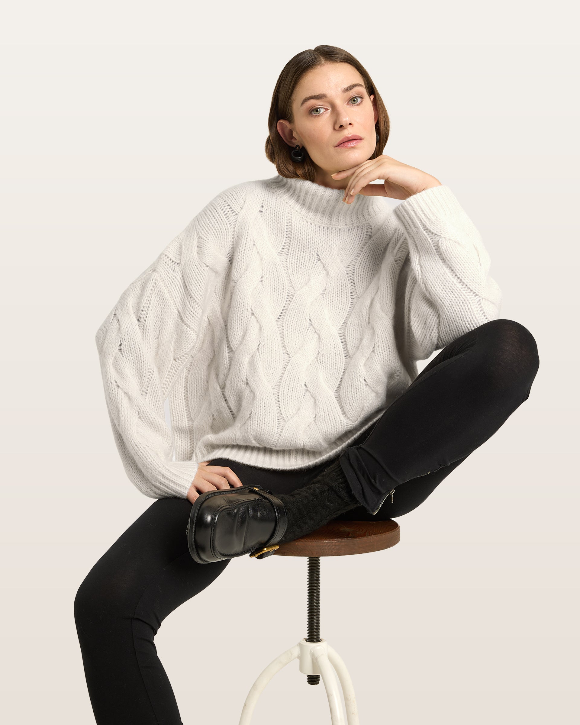 Damen Pullover aus 75 % Kaschmir und 25 % Seide in Ivory – grob gestrickter Pullover mit Zopfstrickmuster in oversized Passform mit langer, weiter Silhouette. Das Modell verfügt über einen hohen Stehkragen in Rippstruktur, eine überschnittene Schulter sowie lange, weite Ärmel. Ärmelbündchen und Saum sind in Rippstruktur gearbeitet und unterstreichen den markanten Strickcharakter des Designs.