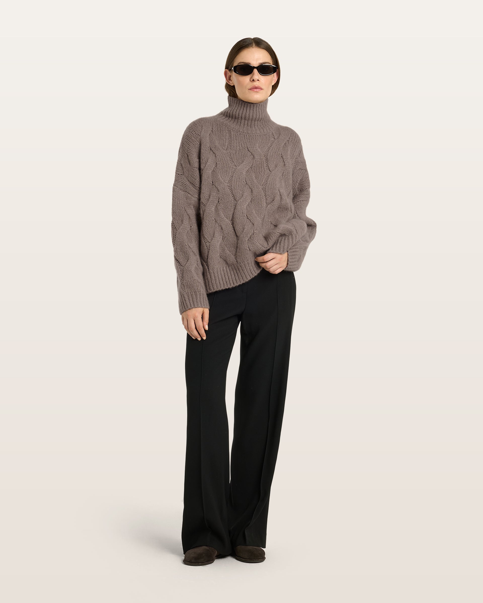 Damen Pullover aus 75 % Kaschmir und 25 % Seide in Natural Twine – grob gestrickter Pullover mit Zopfstrickmuster in oversized Passform mit langer, weiter Silhouette. Das Modell verfügt über einen hohen Stehkragen in Rippstruktur, eine überschnittene Schulter sowie lange, weite Ärmel. Ärmelbündchen und Saum sind in Rippstruktur gearbeitet und unterstreichen den markanten Strickcharakter des Designs.