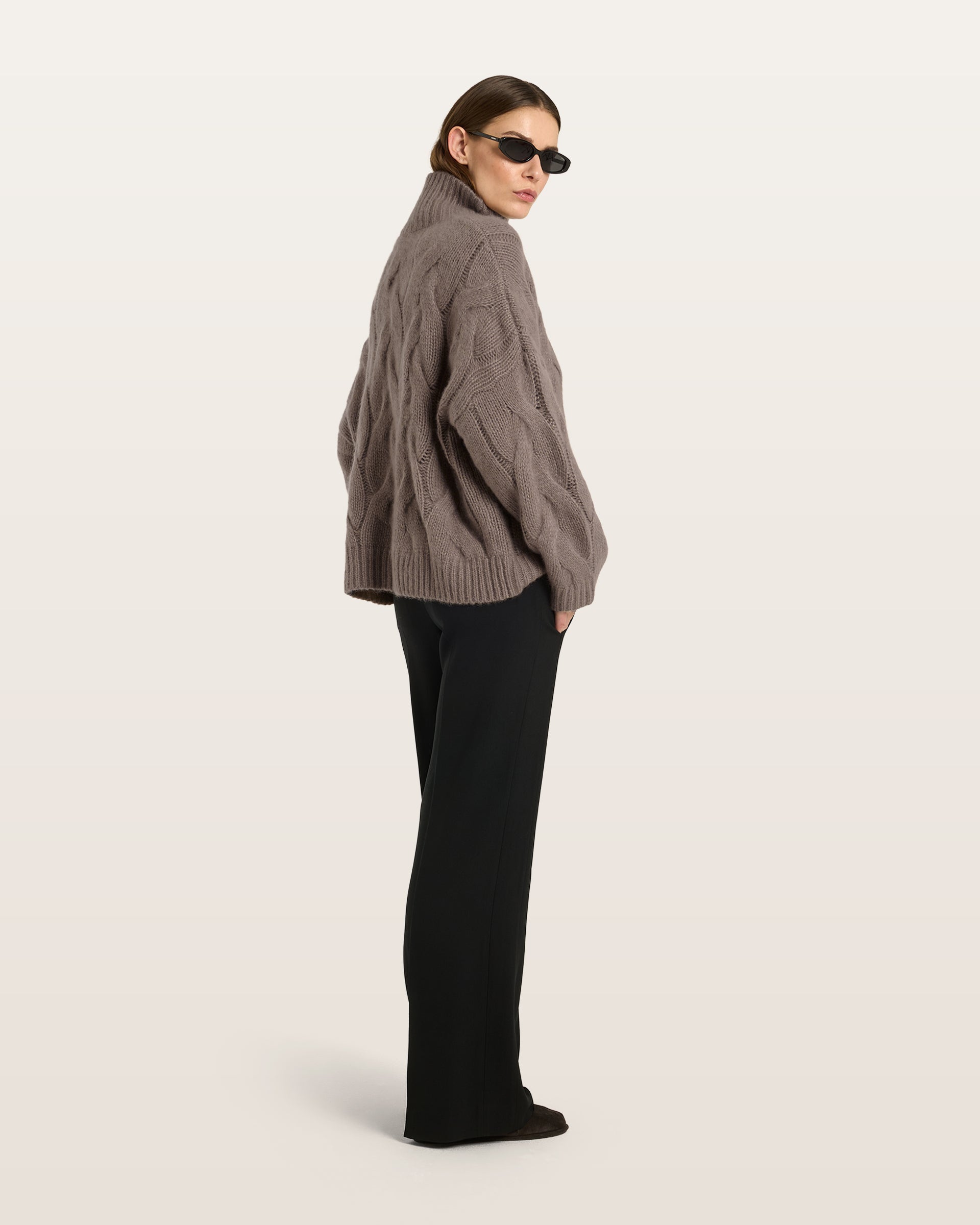 Damen Pullover aus 75 % Kaschmir und 25 % Seide in Natural Twine – grob gestrickter Pullover mit Zopfstrickmuster in oversized Passform mit langer, weiter Silhouette. Das Modell verfügt über einen hohen Stehkragen in Rippstruktur, eine überschnittene Schulter sowie lange, weite Ärmel. Ärmelbündchen und Saum sind in Rippstruktur gearbeitet und unterstreichen den markanten Strickcharakter des Designs.